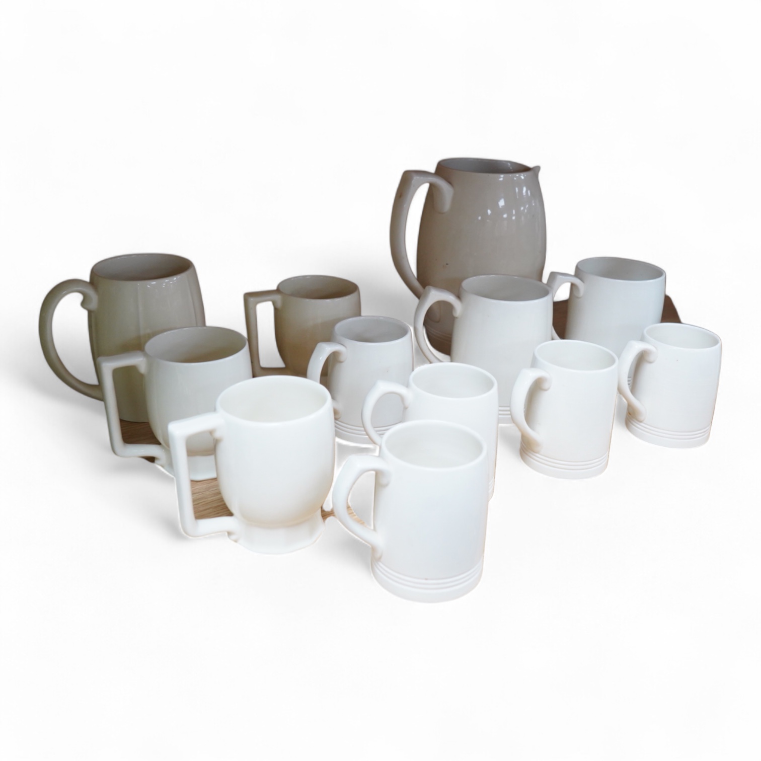 Keith Murray for Wedgwood, a cream lemonade jug, five small mugs, two large three faceted, largest 21cm high (12)